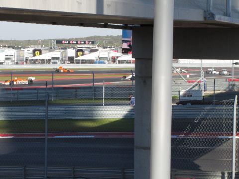 2006 BMW 5 Series - Multiple Formula 1 cars compete on a race track, with pit lane structures visible.