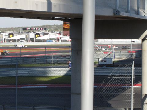 2006 BMW 5 Series - Multiple race cars are visible on a circuit with pit lane structures in the background.