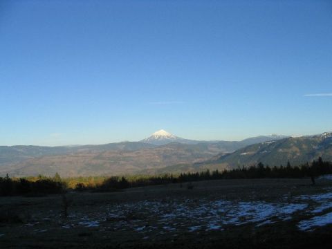 1988 Ford Bronco - A vast mountain range stretches across the horizon under a bright blue sky, with patches of snow visible in the foreground.