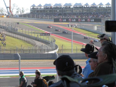 2006 BMW 5 Series - Spectators watch race cars compete on a track, with grandstands filled with people in the background.