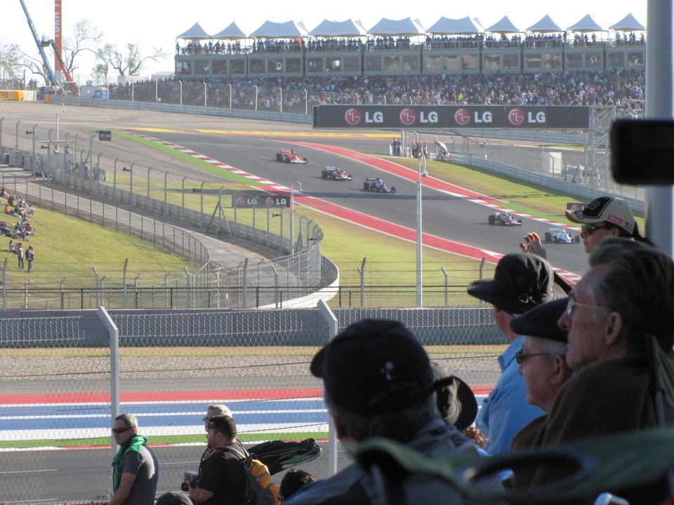 Race cars on a track with spectators in the foreground