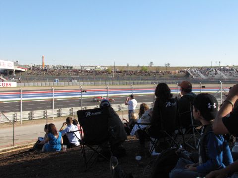 2006 BMW 5 Series - Race day at the circuit with crowds in the stands and cars on the track.