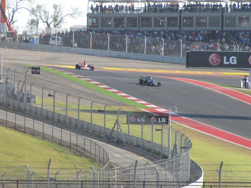Two race cars on a track with grandstands and LG signage