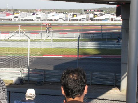 2006 BMW 5 Series - A red race car is seen on the track at the Circuit of the Americas, with spectators in the foreground.
