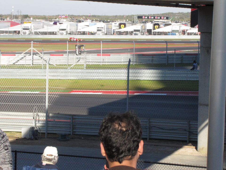 Red race car on a track with grandstands in the background