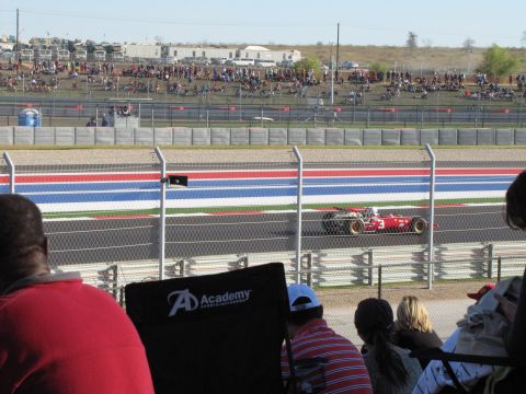 2006 BMW 5 Series - A red Formula 1 race car competes on a track with spectators watching from the stands.