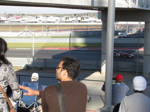 2006 BMW 5 Series - A race car speeds around a track, with spectators watching from above.