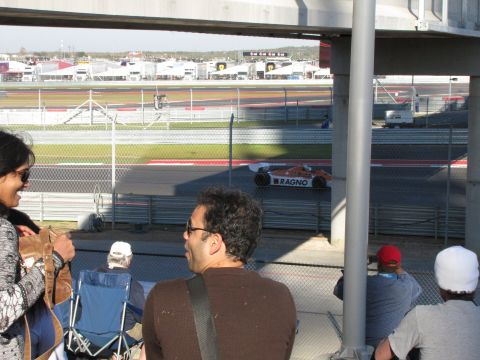 2006 BMW 5 Series - A race car with RAGNO branding speeds around a track, viewed from the spectator area.