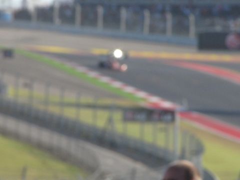 2006 BMW 5 Series - A race car speeds around a track, its headlight shining brightly.