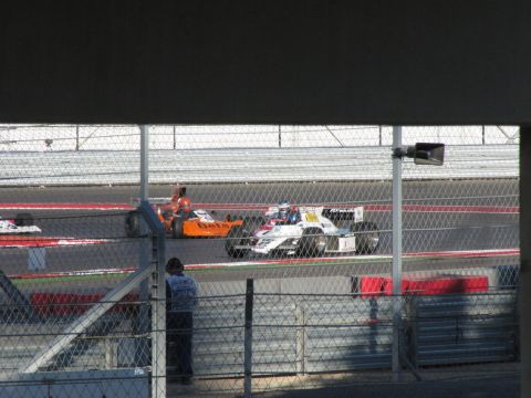 2006 BMW 5 Series - Race cars compete on a track, with a spectator watching from the side.