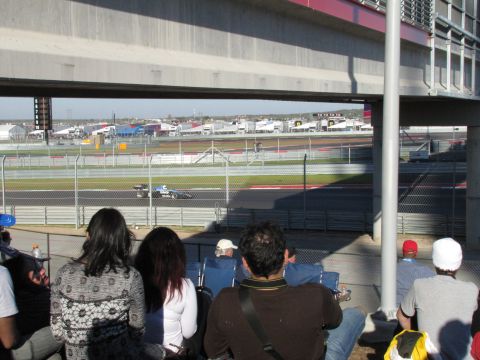 2006 BMW 5 Series - Spectators watch a race car speed around a track from the grandstands.