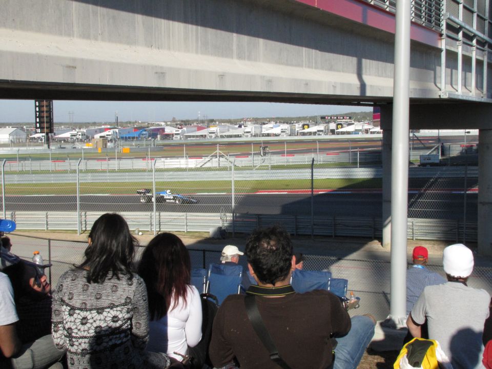 Race car on track viewed from grandstands. People watching