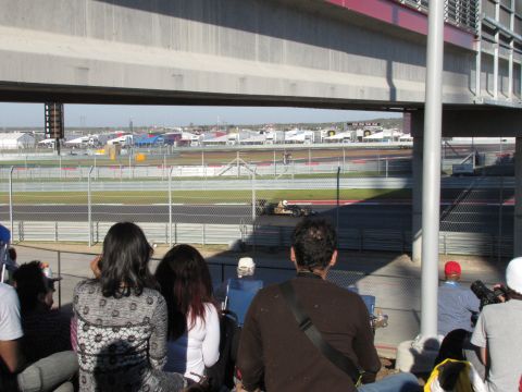 2006 BMW 5 Series - A race car speeds around the track at the Circuit of the Americas, viewed from the stands.
