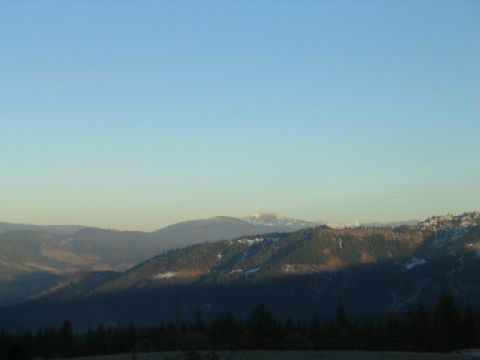 1988 Ford Bronco - A vast expanse of mountains under a clear blue sky, with a prominent shadow stretching across the terrain.