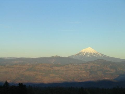 1988 Ford Bronco - A mountain peak, dusted with snow, stands tall against a blue sky, overlooking rolling hills.