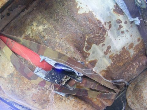 1996 Ford Bronco - The interior floor shows significant rust and damage, with a seatbelt and camouflage fabric visible.