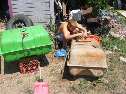 1996 Ford Bronco - A boy works on a rusty fuel tank outdoors, with another green fuel tank nearby.