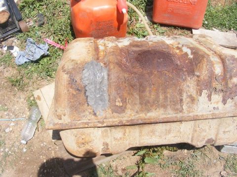 1996 Ford Bronco - A heavily rusted fuel tank sits outdoors, with two gas cans nearby.