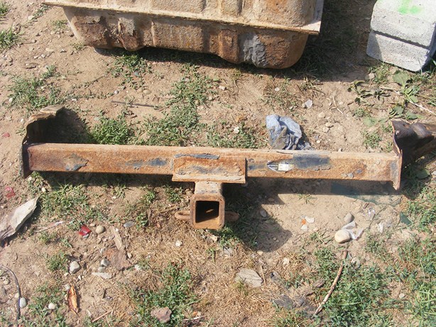Rusted trailer hitch receiver with a square opening and a loop for a pin