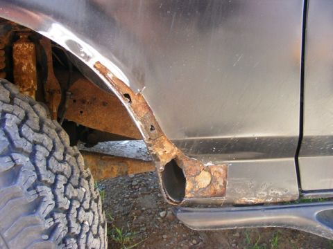 1996 Ford Bronco - The vehicle's rear wheel well shows extensive rust damage, compromising the structural integrity of the fender and frame.