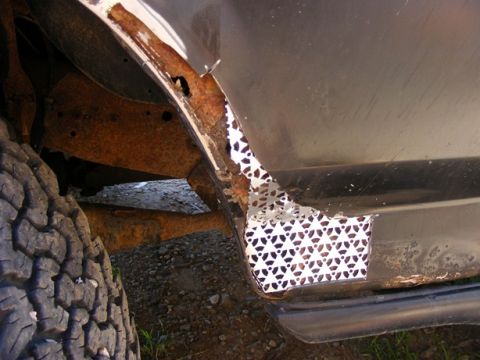 1996 Ford Bronco - The vehicle's wheel well shows significant rust damage and a poorly applied metal patch.