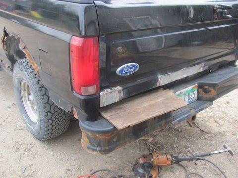 1996 Ford Bronco - This 1992 Ford Bronco shows extensive rust on the rear quarter panel and bumper, with a piece of wood covering the damaged area.