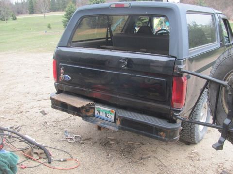 1996 Ford Bronco - The rear of a black Ford Bronco is shown, with a spare tire mounted externally and a license plate reading 2KJ U25.