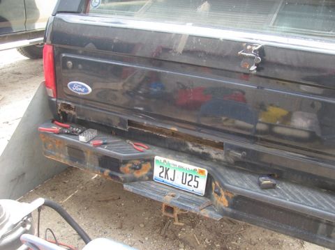 1996 Ford Bronco - The rear of a black Ford truck shows a license plate and tools on a rusty bumper.