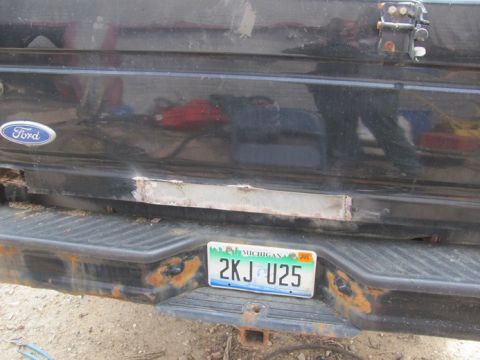 1996 Ford Bronco - Rear view of a black Ford vehicle showing the tailgate, bumper, and a Michigan license plate with some rust.