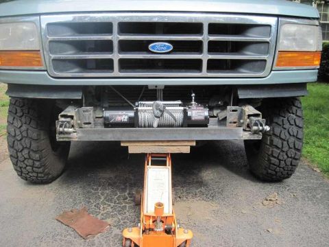 1996 Ford Bronco - The front of a green Ford Bronco is shown with a winch and jack, indicating it is being worked on.