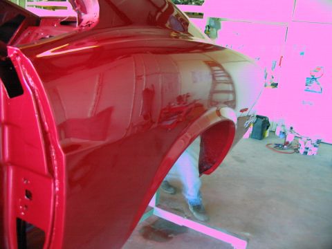 1970 Ford Mustang - Close-up of a shiny red car fender and door, possibly undergoing restoration or repair.