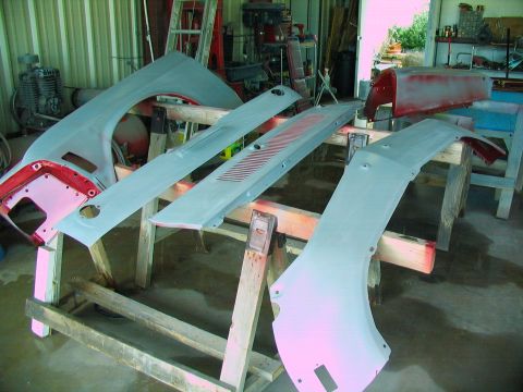 1970 Ford Mustang - Various car body panels are laid out on sawhorses, ready for painting in a workshop.