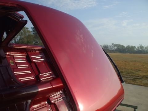 1970 Ford Mustang - Bare interior of a red car, possibly undergoing restoration, with the trunk lid open.