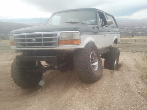 1994 Ford Bronco - Modified Ford Bronco with custom suspension and oversized tires sits on a dusty incline.