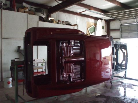 1970 Ford Mustang - The underside of a car body is visible as it is worked on in a garage.