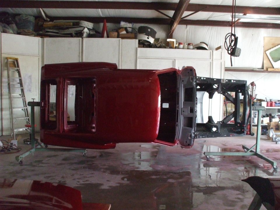 Red 1970 Ford Mustang body on rotisserie, upside down