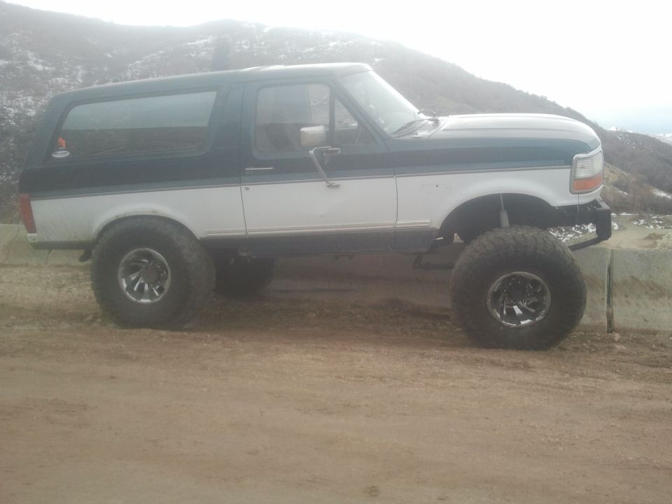 1994 Ford Bronco lifted with large tires, parked on dirt road