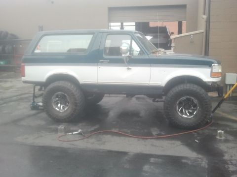 1994 Ford Bronco - Side view of a lifted 1994 Ford Bronco with custom wheels and tires.