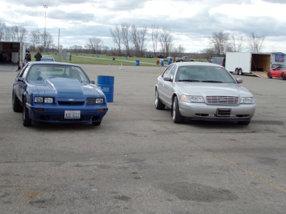Silver Crown Victoria and a blue Mustang drag car parked on asphalt