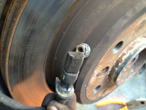 1999 BMW 5 Series - A mechanic's hand holds a broken ABS sensor near a worn brake rotor.