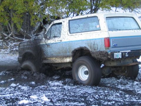 1988 Ford Bronco - Muddy 1988 Ford Bronco struggling off-road in snowy conditions.