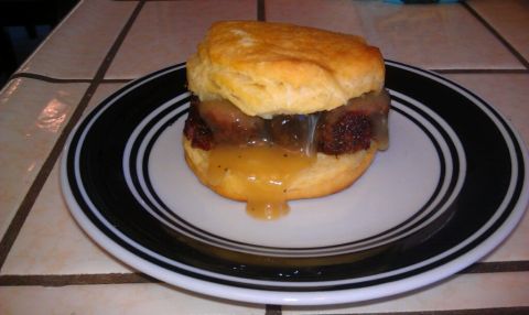 1989 Ford Bronco - A close-up of a biscuit sandwich, generously topped with gravy and meat, served on a black and white striped plate.