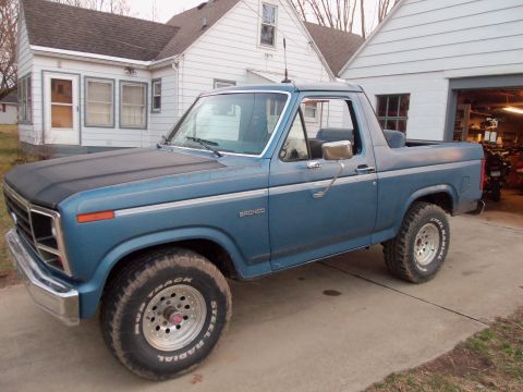 1985 Ford Bronco - This blue Ford Bronco is parked in front of a house and garage.