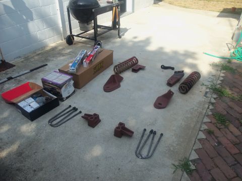 1985 Ford Bronco - Collection of vehicle suspension parts and a grill on a patio.