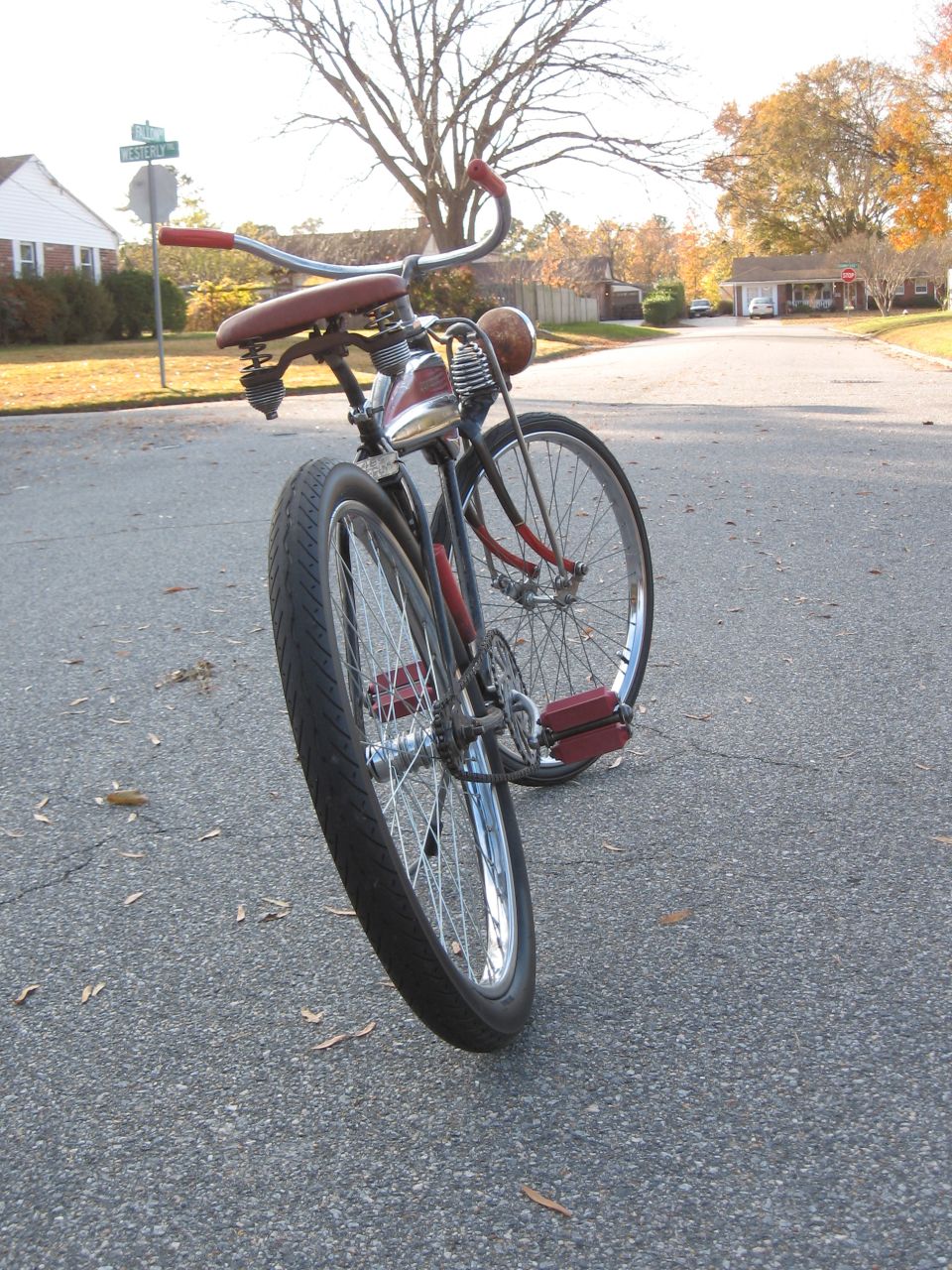 Old bicycle with red handlebars and seat, parked on a street
