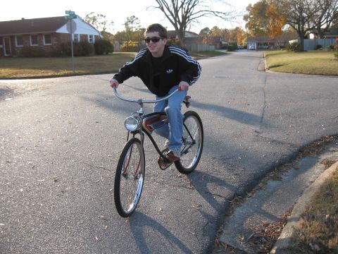 1994 Ford Bronco - A person rides a vintage bicycle on a paved road in a residential neighborhood.
