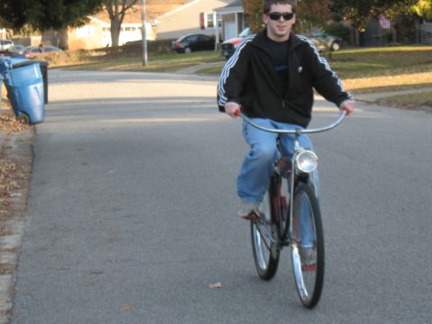 1994 Ford Bronco - A person rides a bicycle down a suburban street with houses and parked cars in the background.