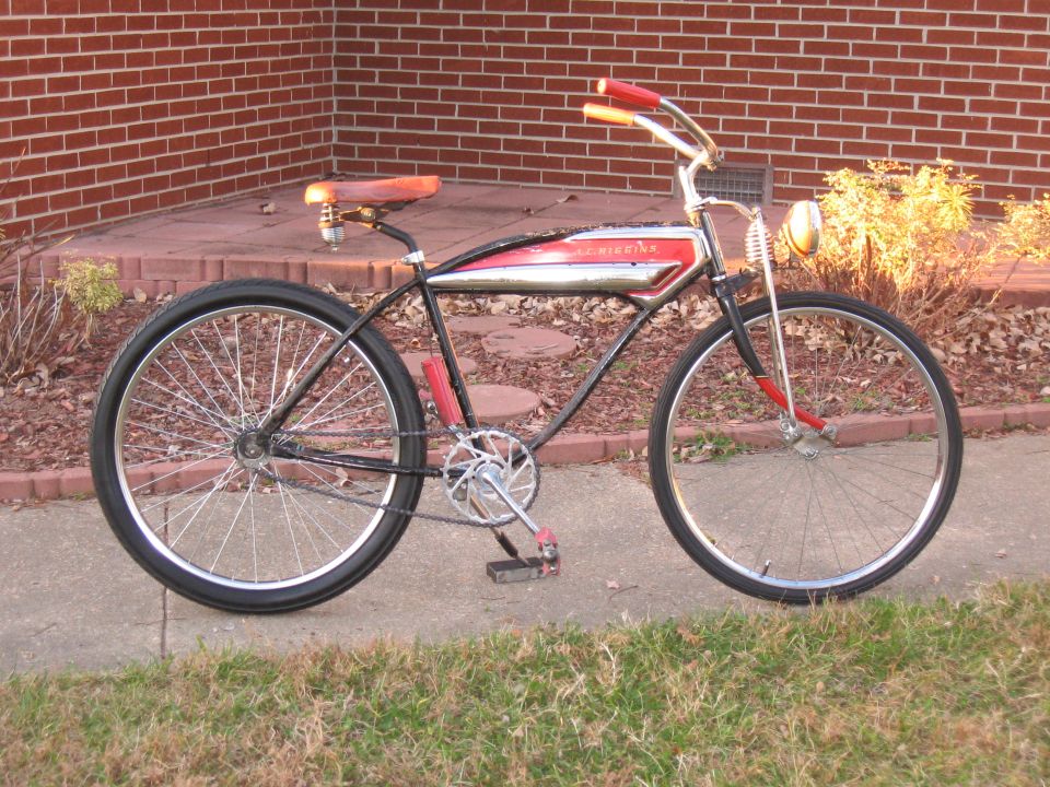 Side view of a red and chrome cruiser bicycle with a leather seat and red handlebars