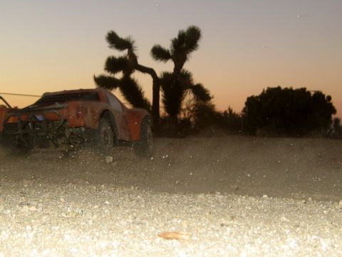 1996 Ford Bronco - An orange RC desert truck drives on a dirt road, kicking up dust against a sunset sky.