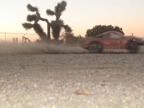 1996 Ford Bronco - An RC truck speeds along a dusty path near a Joshua tree at sunset.